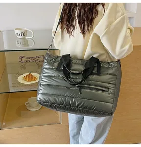 Detailed view of a large metallic grey quilted puffer tote bag featuring a shoulder strap