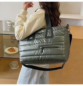 Detailed side view of a large metallic green padded tote bag worn by a model in a cafe