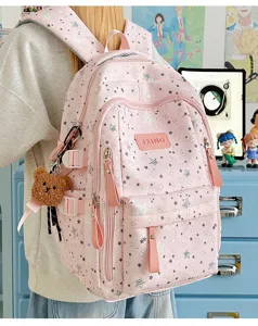 Vista posteriore di uno zaino rosa con motivi a stella e un simpatico portachiavi a orso