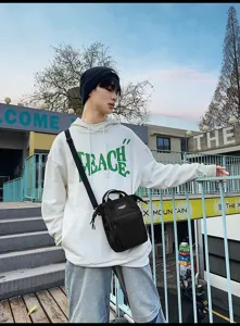 Close-up van een stijlvolle zwarte mini crossbodytas gedragen door een model in een stad