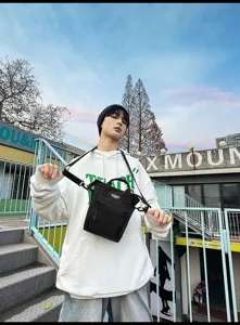 Trendy jonge man met een zwarte mini crossbody-tas in een stedelijke buitenomgeving