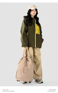 Model carrying a lightweight beige nylon drawstring travel backpack in a studio setting.
