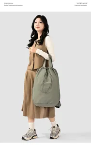 Asian model showcasing a large olive green nylon drawstring backpack in a studio setting