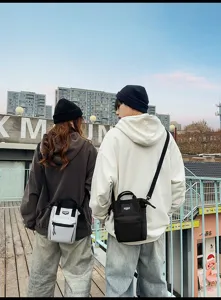 Twee mensen dragen stijlvolle crossbody-tassen voor telefoons in een stedelijke omgeving