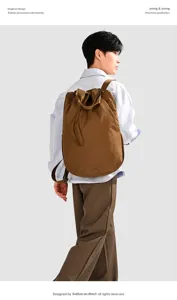 Detailed back view of a minimalist brown nylon travel backpack worn by a male model