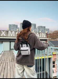 Detail van een stijlvolle kleine grijze rugzak gedragen als crossbody tas voor buiten.