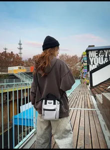 Gedetailleerd overzicht van de stijlvolle lichtgrijze mini-crossbodytas in een stedelijke omgeving