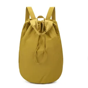 Lightweight yellow nylon drawstring backpack with top handles and adjustable straps for travel.