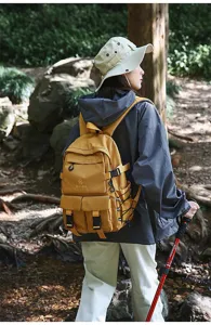 Vista posteriore di uno zaino da trekking giallo indossato da un escursionista nella foresta