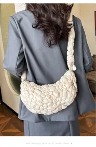 Back view of a model wearing a cream bubble pleated cloud hobo bag with a blue blazer