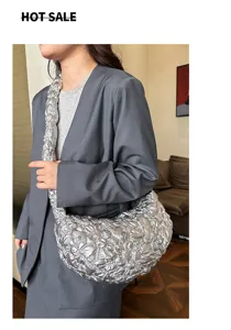 Trendy silver metallic pleated cloud bag shown on model in a stylish lifestyle setting
