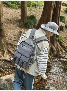 Modello che indossa uno zaino tattico grigio multitasche in una foresta all'aperto