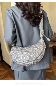Detailed view of a silver puffy pleated cloud bag worn with a stylish gray blazer
