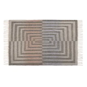 Detailansicht einer nordischen Decke aus Mohair-Imitat mit geometrischem Muster und Fransen.