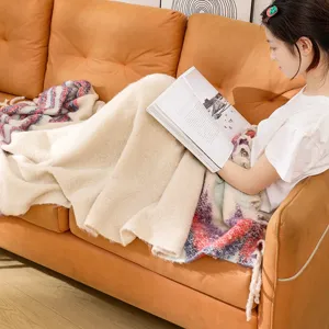 Young woman relaxing on an orange sofa with a thick cream white boucle woven throw blanket