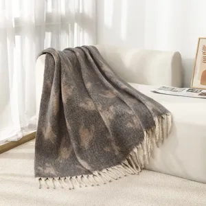 Manta elegante de imitación de mohair con borlas en un sofá blanco en una habitación soleada