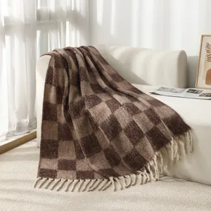 Detail shot of faux mohair bouclé plaid blanket with elegant fringe tassels on sofa
