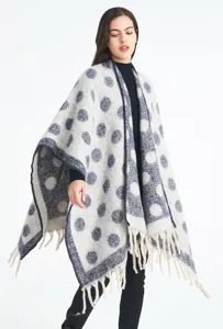 Chal grueso de mezcla de mohair con lunares y borlas en una modelo, fondo blanco.