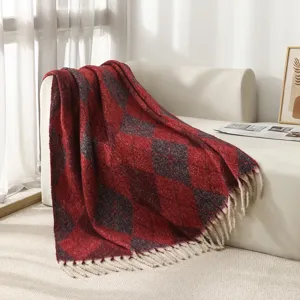 Plaid douillet à carreaux argyle rouge et gris avec franges blanches sur un canapé