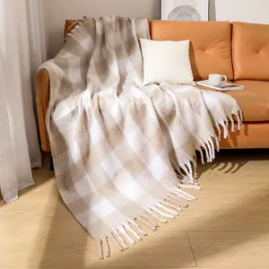 Manta de cuadros de imitación de mohair con flecos elegantes en un sofá de cuero marrón.