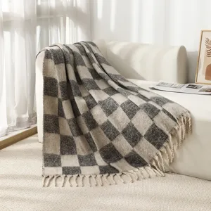 Close-up detail of soft checkered mohair yarn blanket with decorative fringe tassels