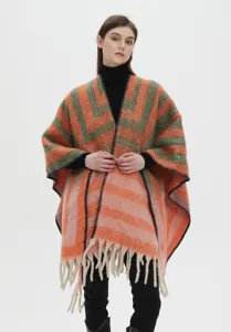 Cozy mohair-like thick striped poncho with fringes worn by model in a studio setting