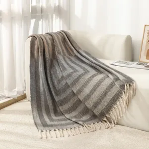 Nordische geometrische Fransen-Wohndecke in Mohair-Optik elegant auf einem Sofa drapiert