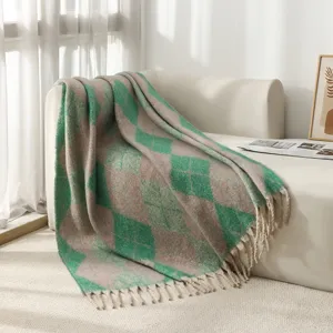 Plaid à losanges en imitation mohair avec pompons drapé sur un canapé blanc moderne