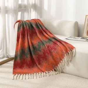 Close-up of ethnic jacquard pattern and tassel fringes on orange mohair-like throw blanket