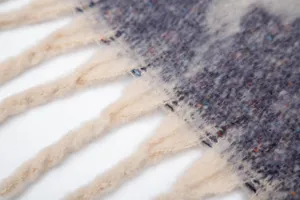 Primer plano de la textura del chal de hilo bouclé tipo mohair con borlas gruesas