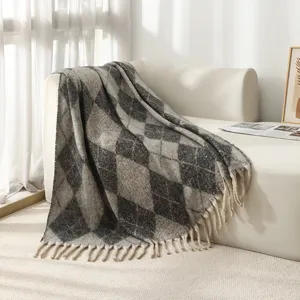 Gros plan d'une couverture jacquard à losanges gris avec des glands décoratifs