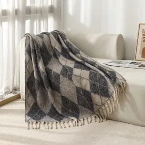 Couverture en faux mohair à motif argyle et franges décoratives sur un canapé blanc