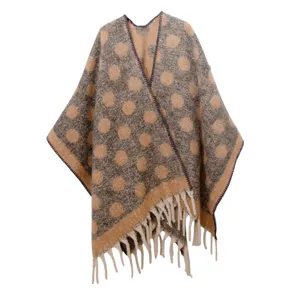 Cálido poncho de hilo bouclé grueso con un elegante patrón de lunares beige y flecos.
