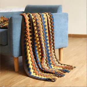 Manta de punto bohemia con patrones de zigzag coloridos sobre un elegante sofá azul