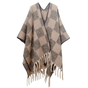 Détail d'un poncho en mohair à carreaux avec pompons et texture en maille jacquard épaisse