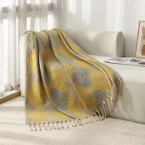 Plaid douillet en fausse mohair à motif argyle jaune et gris avec pompons décoratifs sur canapé
