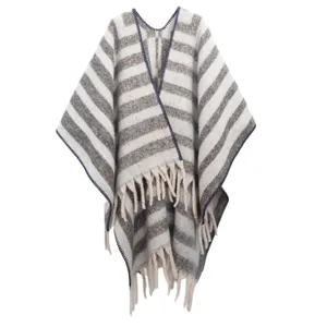 Macro detail of thick striped knit poncho featuring soft boucle yarn and fringe edges.