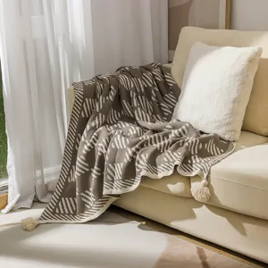 Soft bohemian geometric knitted throw blanket with elegant tassel fringe on a sofa