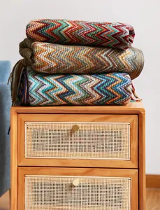 Textura detallada de mantas de punto zigzag bohemias apiladas en una mesita de noche de madera