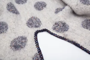 Primer plano de un chal de mohair grueso con lunares jacquard y un borde de ganchillo fino