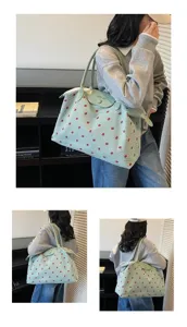Vista dettagliata di una grande borsa da viaggio verde con stampa fragola indossata da una modella
