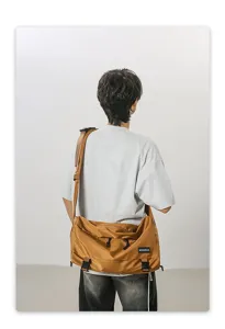 Rückansicht einer Person mit einer großen senfbraunen Kuriertasche für Reise oder Sport