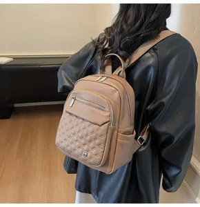 Detail view of brown quilted soft leather fashion backpack for women on model back