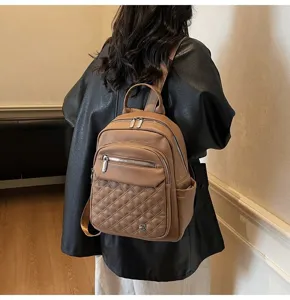 Detailed back view of a stylish quilted brown leather backpack worn by a female model