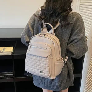 Detailed back view of beige quilted leather backpack worn by model in a library setting