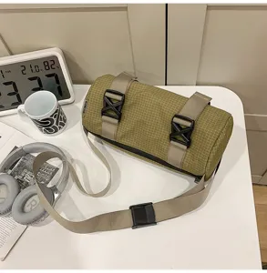 Cylindrical grid patterned crossbody sports bag on a desk with lifestyle accessories