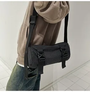 Close-up of a black checkered cylindrical crossbody bag in workwear style details