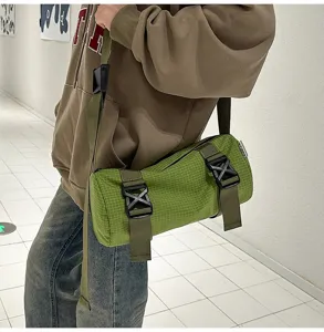 Detail view of a green grid pattern cylinder crossbody bag with army green straps