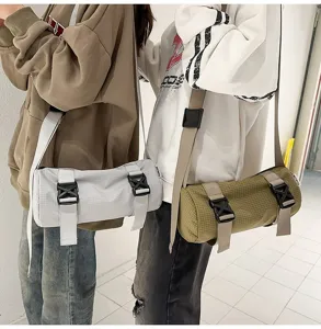 Workwear style cylinder crossbody bags in grey and olive green with buckle straps