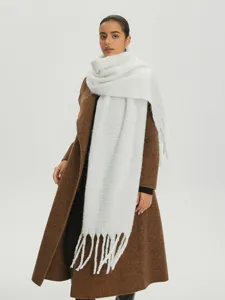 Dettaglio della morbida trama tipo mohair e delle spesse nappe di questa sciarpa bianca.
